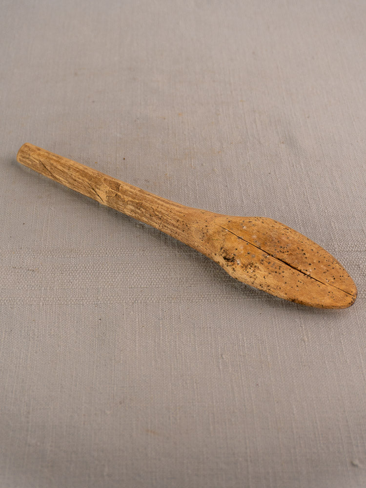 Antique French wooden mortar and pestle, hand-carved, on a light gray fabric background.