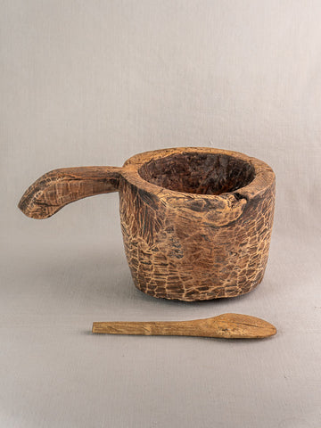Antique French wooden mortar and pestle with hand-carved details and rustic patina on neutral surface.