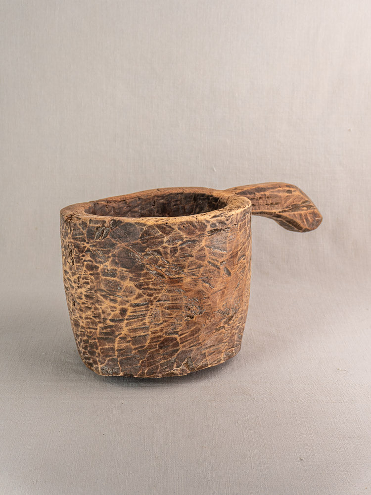 Antique French wooden mortar and pestle, hand-carved, displayed on neutral fabric background.