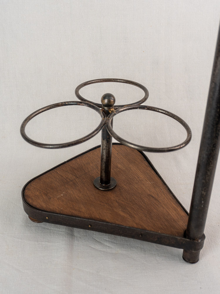 Antique French wrought iron and wood bottle carrier with three circular holders on a wood base.