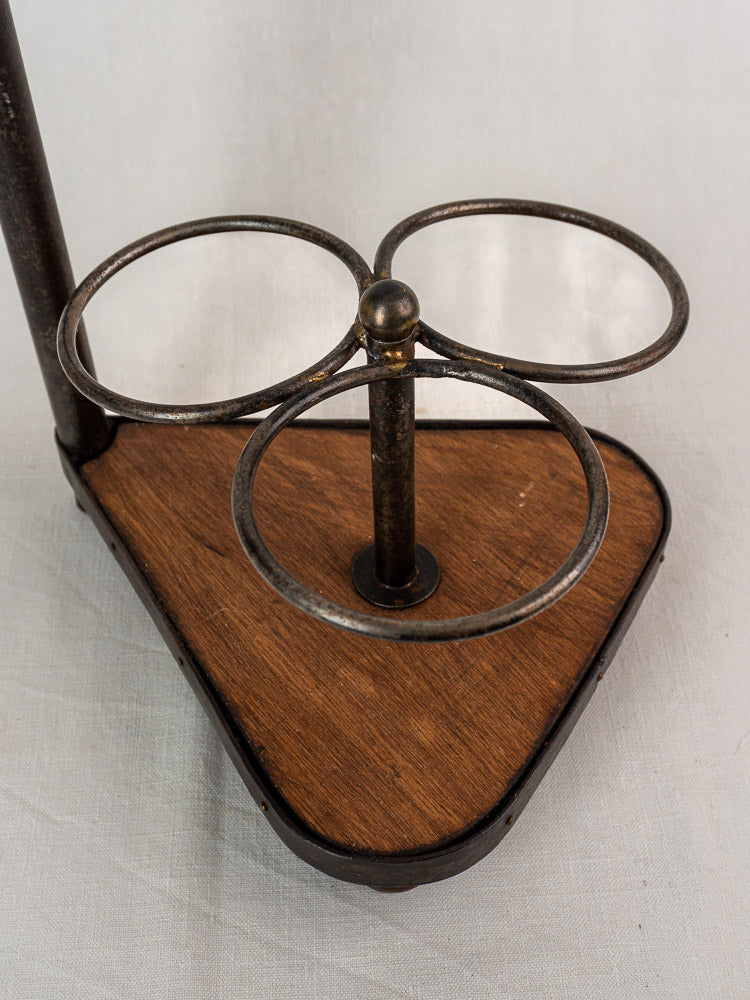 Antique French wrought iron and wood bottle carrier with three rings on a triangular base.