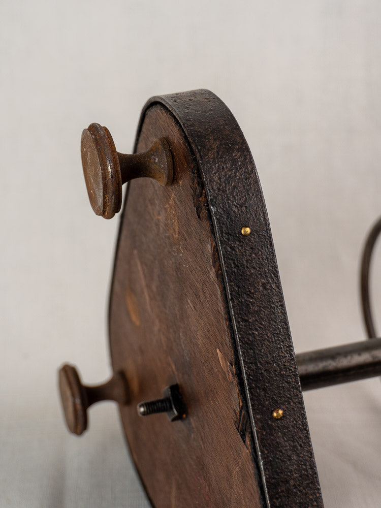 Close-up of round wooden seat base with dark finish, metal screws, and visible wear.