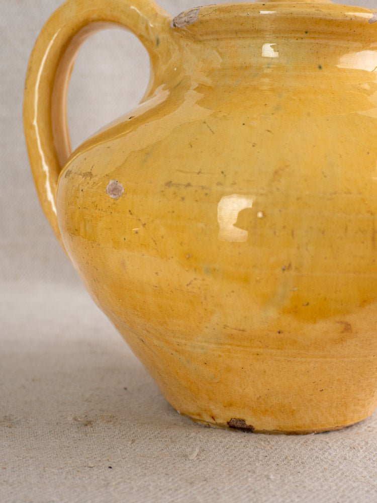 Antique French yellow glazed earthenware teapot with single handle, glossy finish, subtle imperfections.