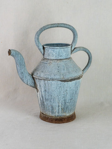 Antique French zinc water pitcher with blue-gray patina, large top handle, long spout on light background.