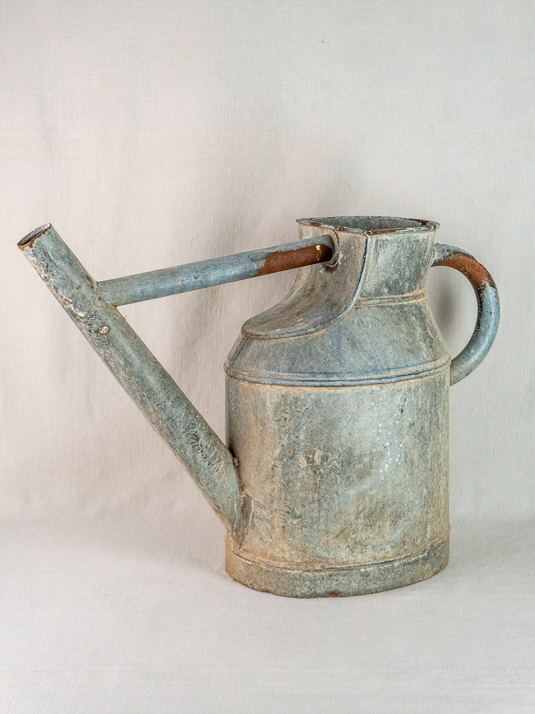Large antique French zinc watering can with weathered metal, rust, and vintage garden patina.