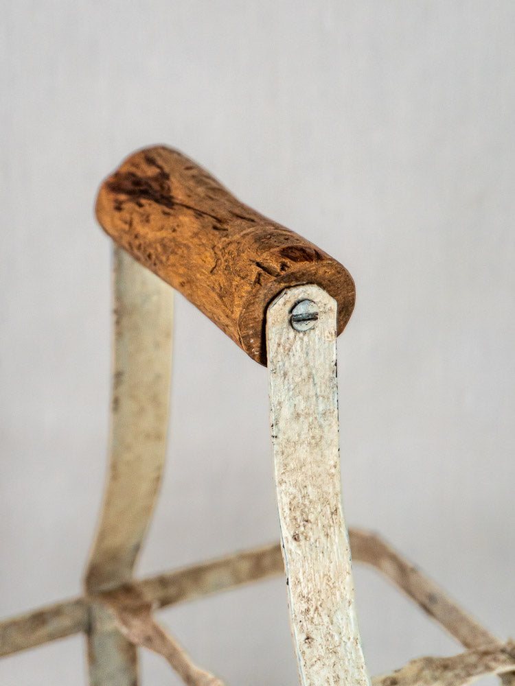Antique French four-bottle painted zinc wine carrier with weathered metal handle and wooden grip on plain background.