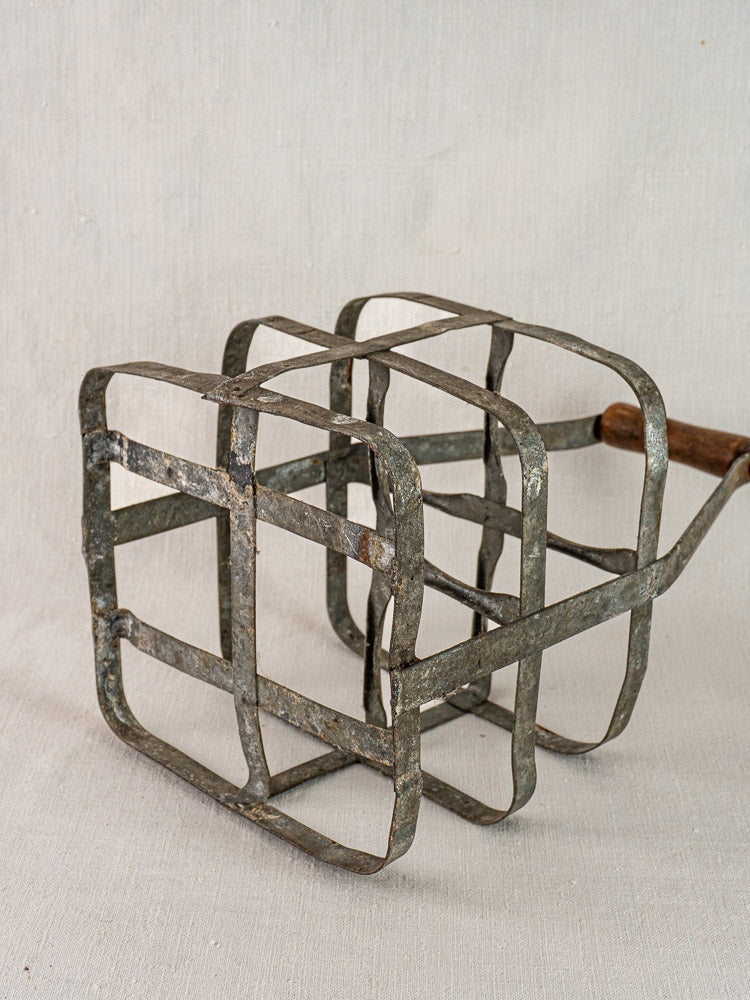 Antique French zinc and wood four-bottle wine carrier with intersecting metal bars and wooden handle.