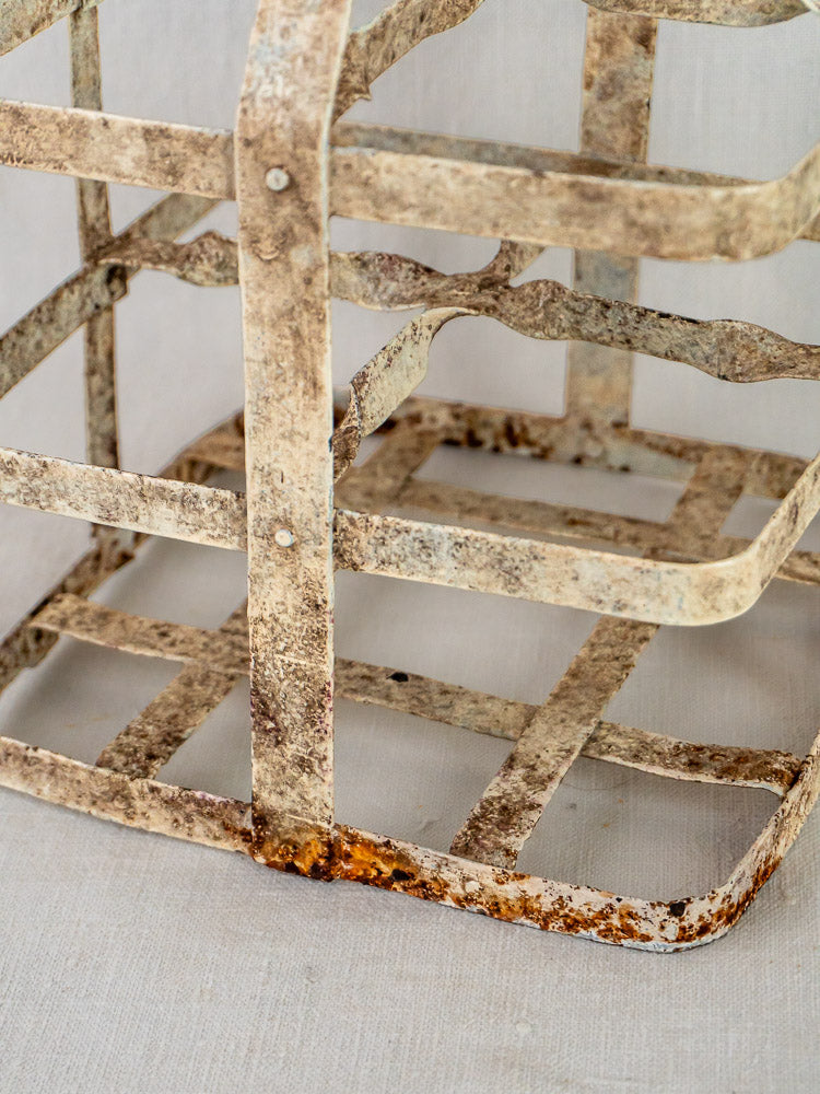 Painted zinc French wine carrier with four square compartments and weathered finish on a neutral background.