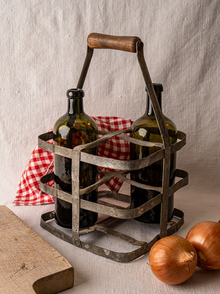 French antique zinc and wood four-bottle wine carrier with two bottles, checkered cloth, onions, and cutting board.