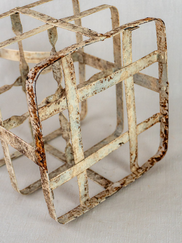 Antique French painted zinc four-bottle wine carrier with grid structure on a light surface.