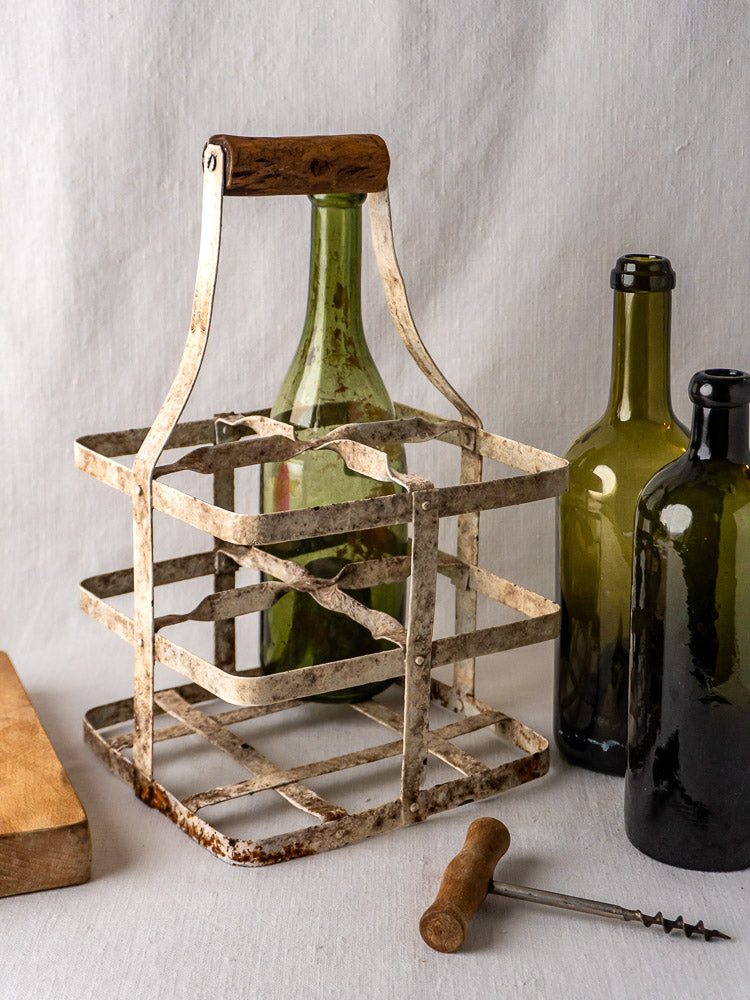 Antique French painted zinc wine carrier with wooden handle, four-bottle porte-bouteilles on light gray background.