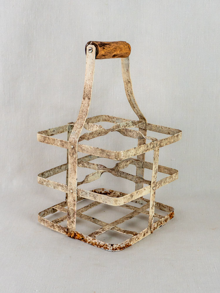 Antique French painted zinc wine carrier with wooden handle, four-bottle porte-bouteilles on light gray background.