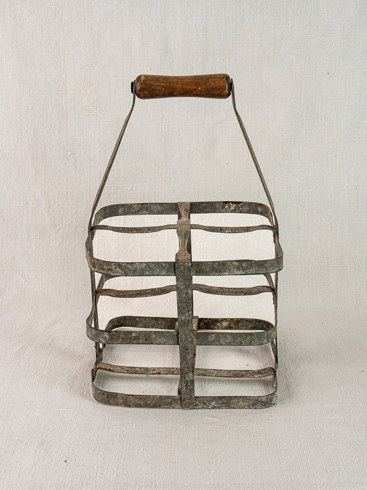Antique French zinc and wood four-bottle wine carrier with curved metal handle and wooden grip.
