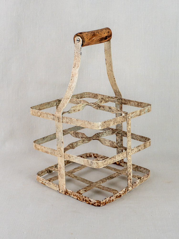 Antique French painted zinc wine carrier with four slots, wooden handle, and weathered patina.