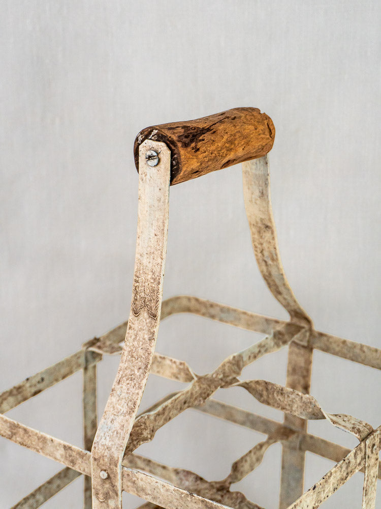 Weathered metal handle with worn wooden grip on rustic French painted zinc wine carrier.