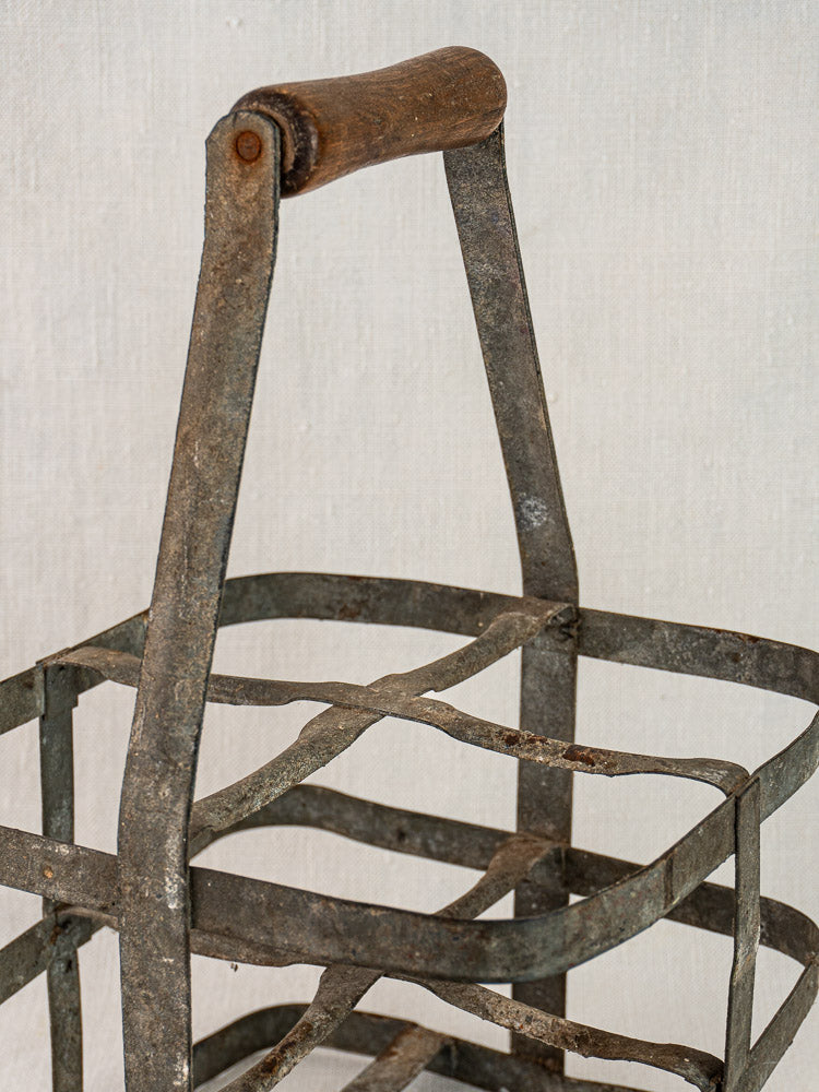 French antique zinc and wood wine carrier with grid metal frame and wooden handle on light fabric.