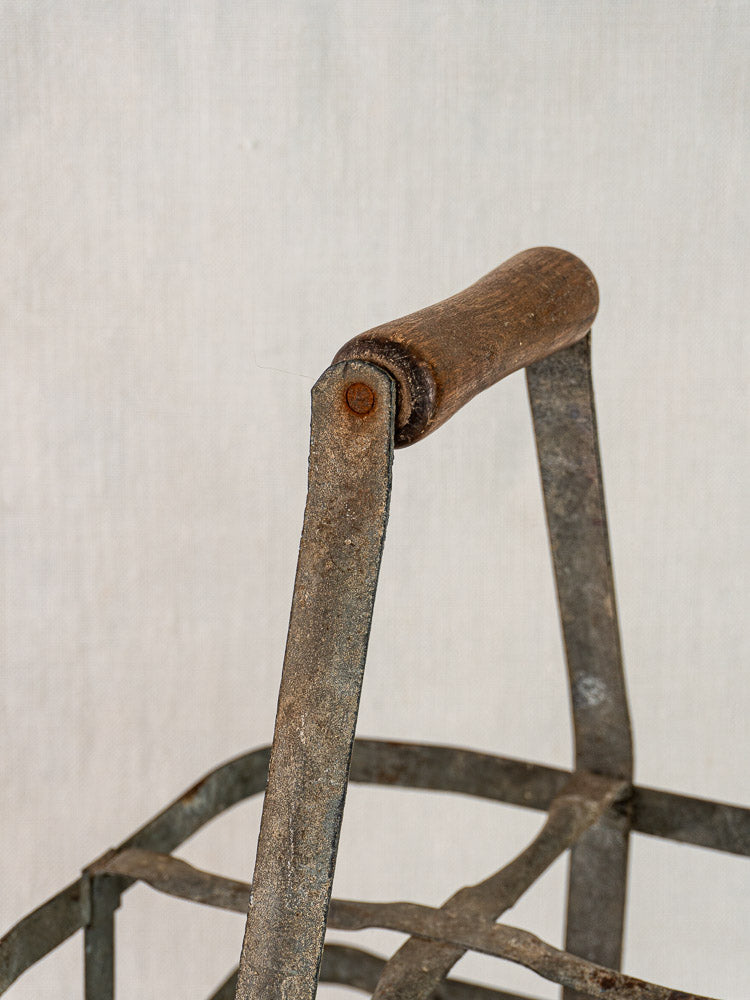 Close-up of wooden handle and weathered metal on French zinc and wood wine carrier, fabric background.