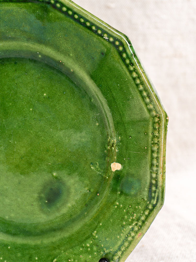 Antique French green glazed octagonal plate with beaded border, glossy finish, and small earthenware chip on light fabric. Pair.