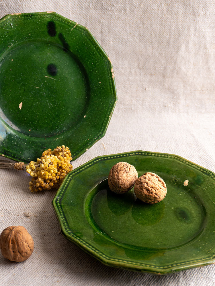Antique French green glazed plates from Drôme on beige cloth, with walnuts and yellow dried flowers as accents.