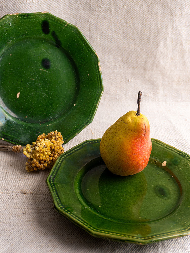 Antique French green glazed plates from the Drôme with a ripe pear and dried yellow flowers on beige fabric.