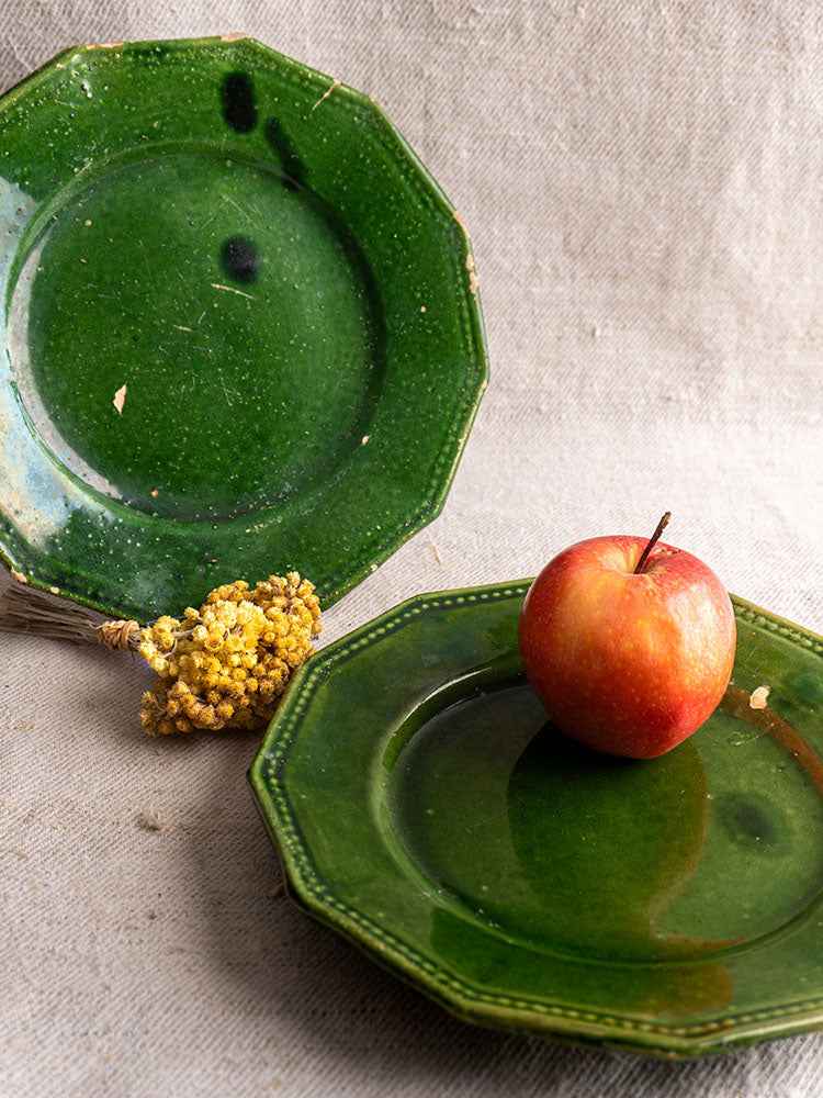 Pair of antique French green glazed plates from Drôme with minor chips, displayed on neutral fabric.