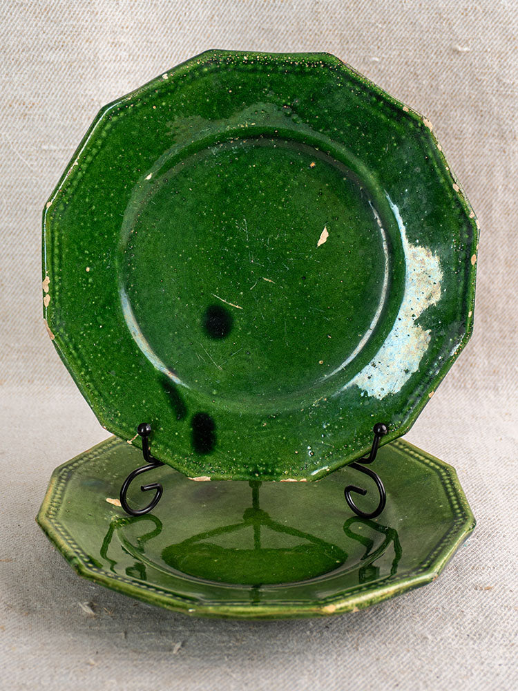 Pair of antique French green glazed plates from Drôme with minor chips, displayed on neutral fabric.