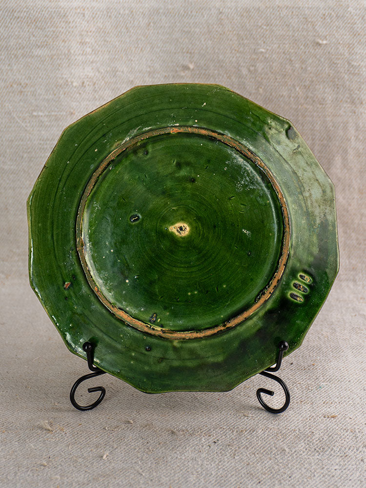 Antique French green glazed octagonal plate from Drôme on black metal stand, glossy finish, visible imperfections.