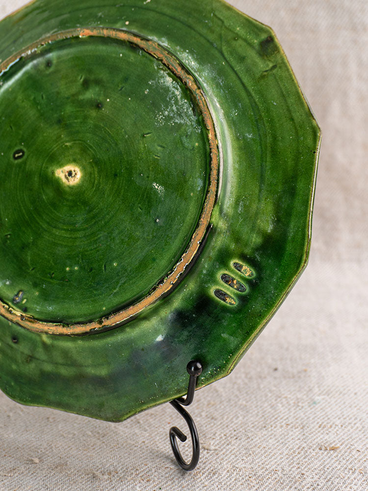 Antique French green glazed plate from Drôme on black metal stand, showing unglazed base and maker’s marks.