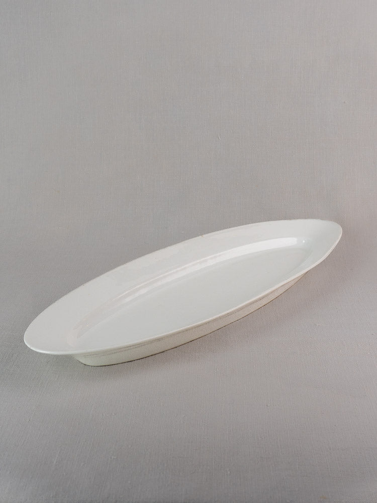 19th-century white ironstone French turbot platter with oval shape and glossy finish on gray background.