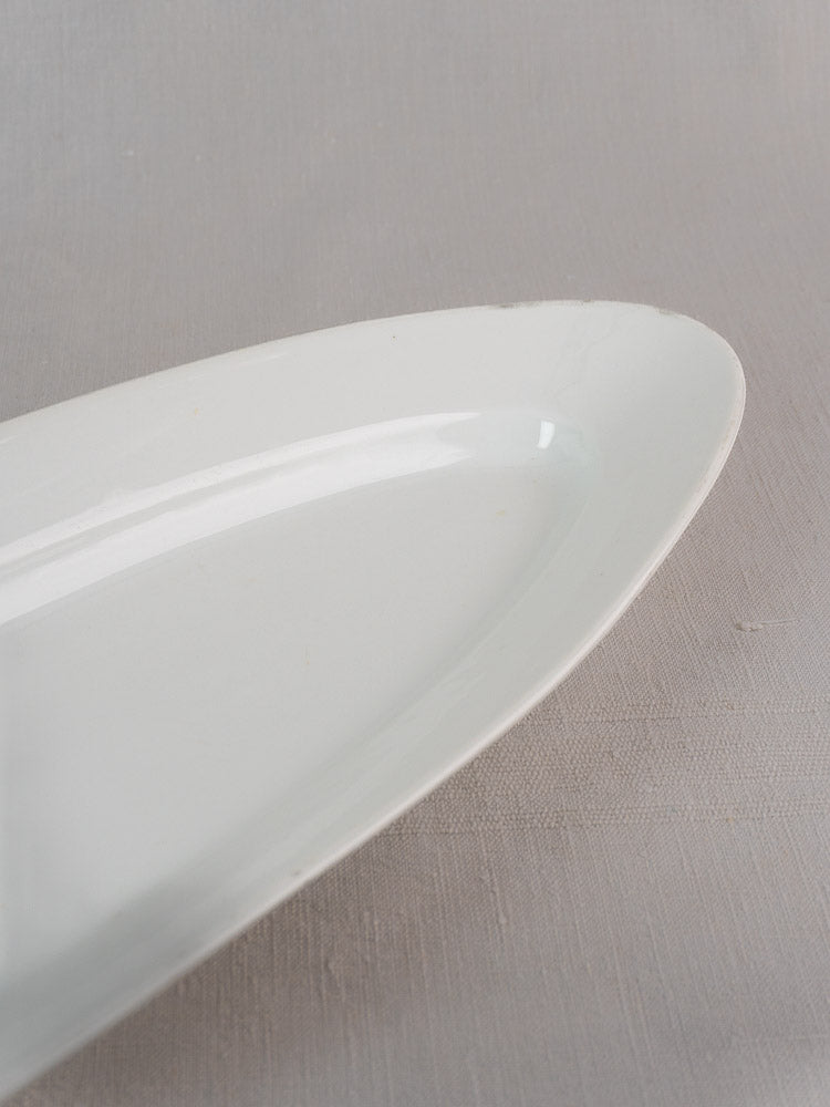 Antique French 19th-century white ironstone fish platter with smooth oval design on gray surface.