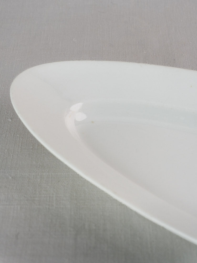Detail of an antique French 19th-century white ironstone turbot platter on gray textured surface.