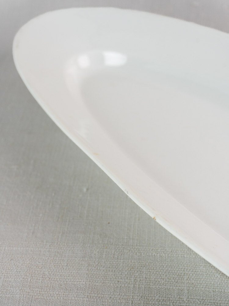 Antique French 19th-century white ironstone fish platter on a light gray textured surface.