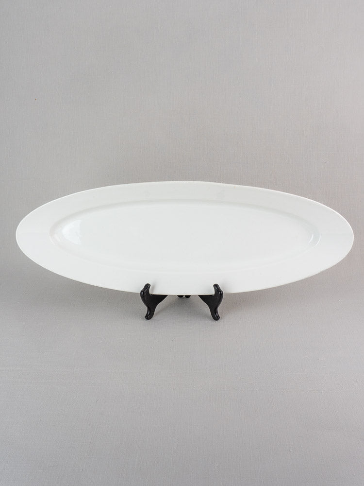 19th-century antique French white ironstone turbot platter displayed on a black stand, gray background.