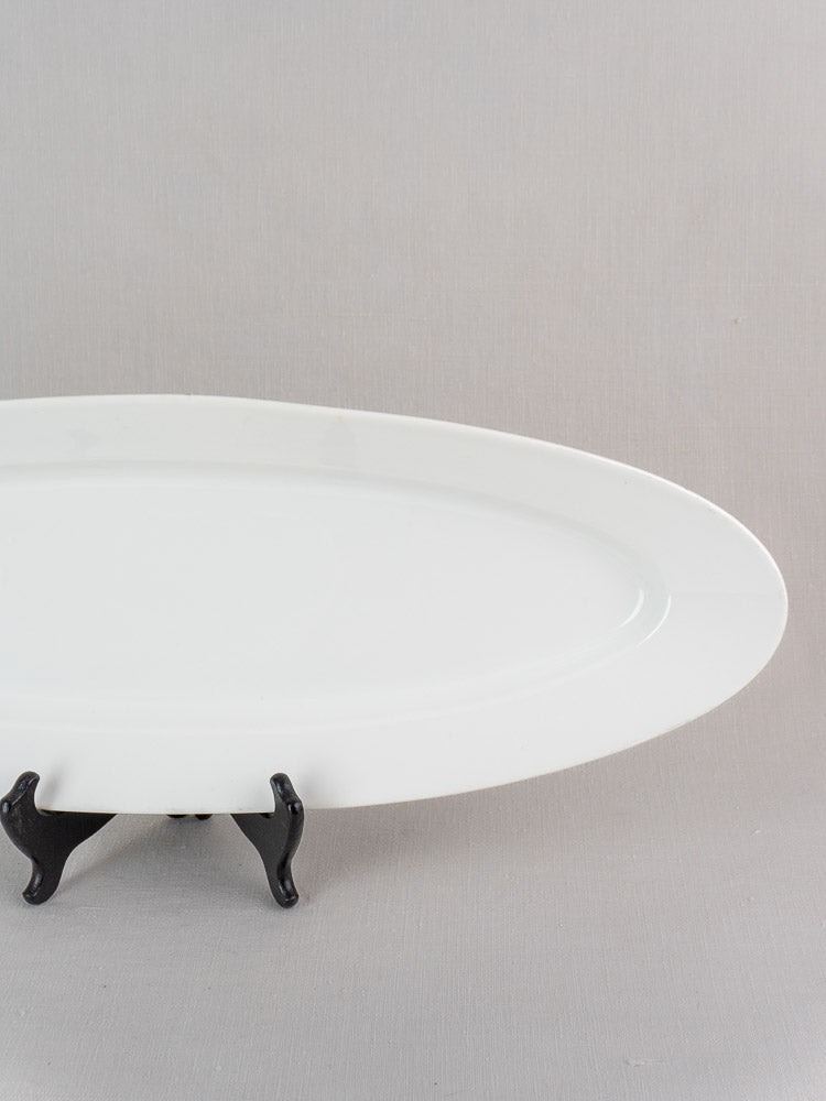 Antique 19th century French white ironstone fish platter with classic oval design on a black stand.