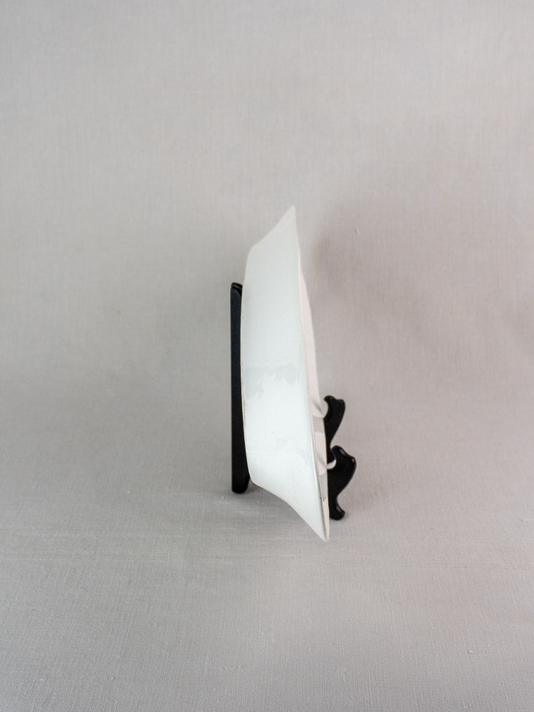 Antique French 19th-century white ironstone turbot platter on black stand, light gray fabric backdrop.