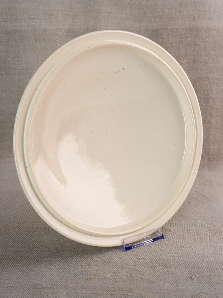 Antique French Longwy ironstone soup tureen in Capucine blue transferware on clear stand, neutral fabric backdrop.