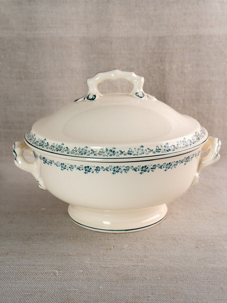 Antique French Longwy ironstone soup tureen with Capucine blue floral transferware, on neutral fabric background.