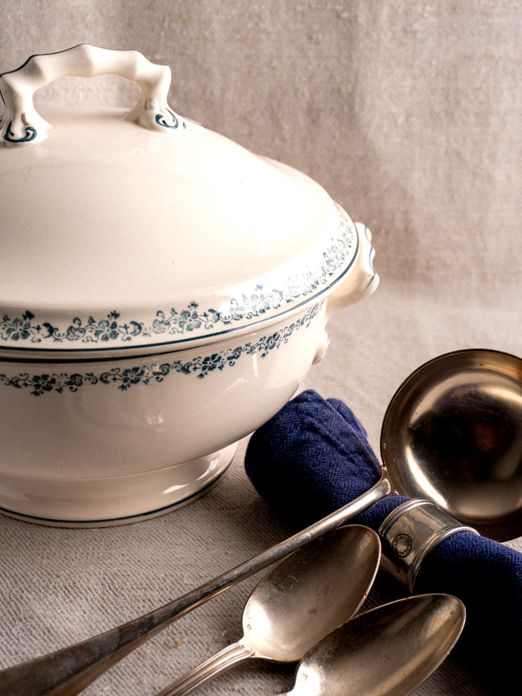 Antique French Longwy ironstone soup tureen with Capucine blue floral transferware, on neutral fabric background.