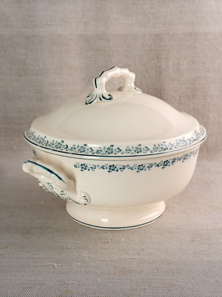 Antique French Longwy ironstone soup tureen with Capucine blue floral pattern and ornate handles on linen.