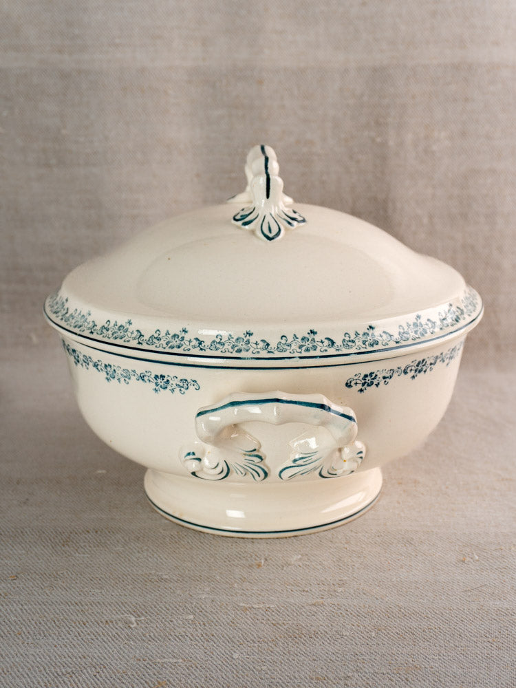 Antique French Longwy ironstone soup tureen with Capucine blue transferware, ornate handles, on beige fabric.