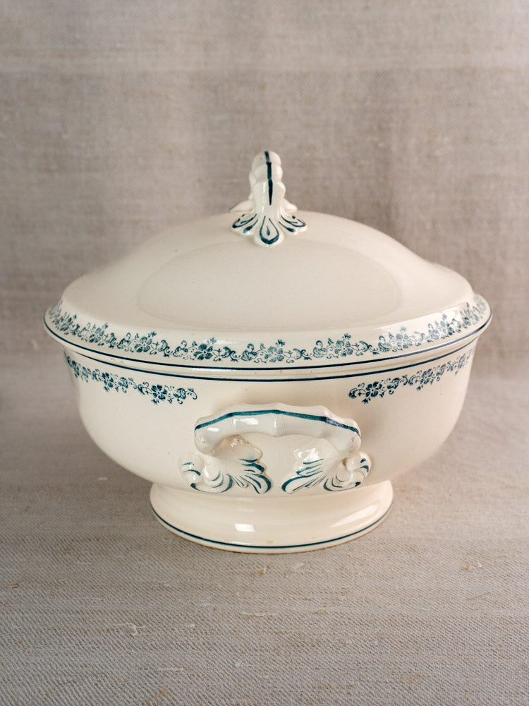 Antique French Longwy ironstone soup tureen with Capucine Blue transferware, ornate handles, and lid on beige fabric.