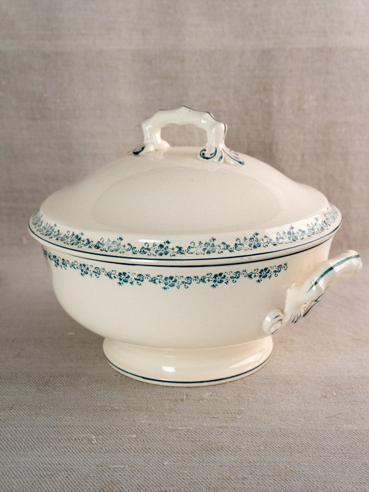 Antique French Longwy ironstone soup tureen with lid, Capucine blue floral pattern, neutral fabric backdrop.