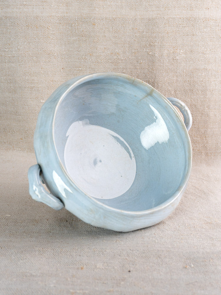 Antique Villeroy and Boch Mettlach tureen with soft blue glaze and two handles on beige fabric.