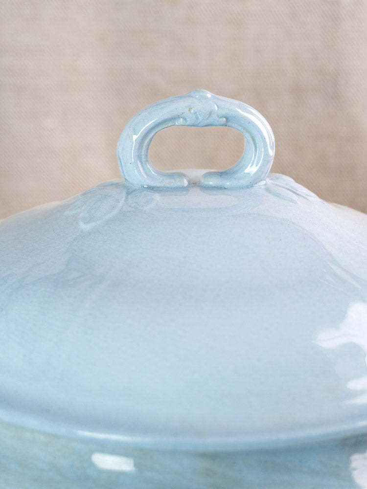 Antique Mettlach tureen by Villeroy and Boch with soft blue glaze and ceramic lid handle on beige background.