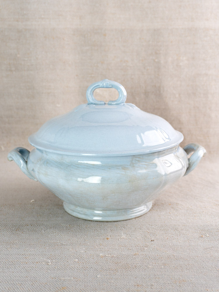 Antique Villeroy and Boch Mettlach tureen with soft blue glaze and lid on beige fabric.