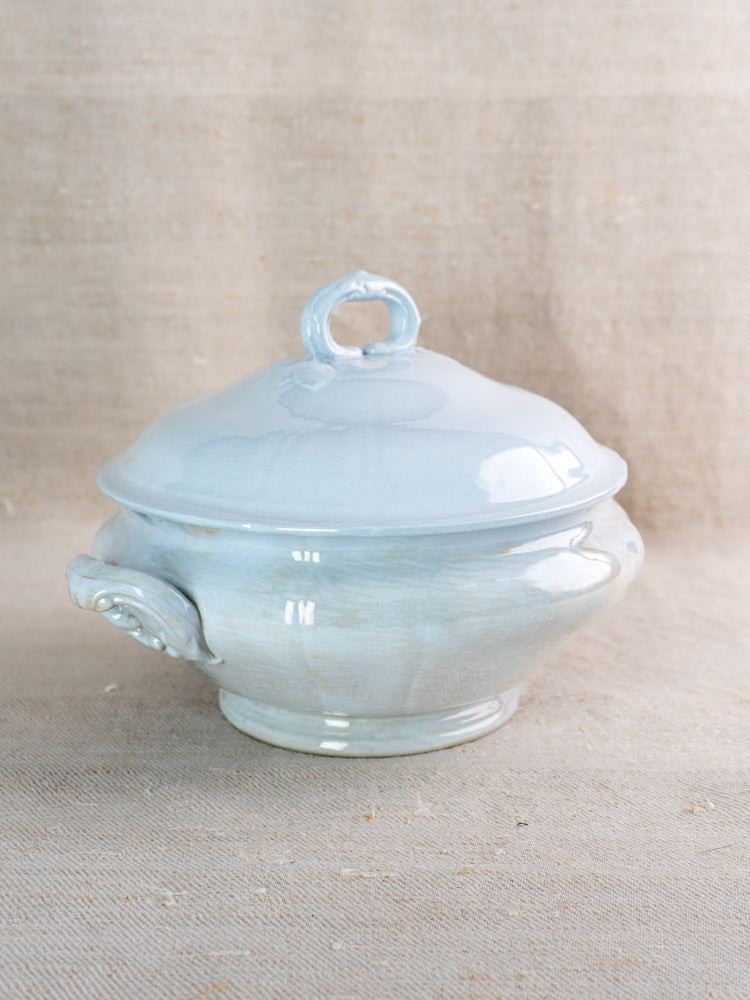 Antique Villeroy and Boch Mettlach tureen with soft blue glaze and ornate handles on beige fabric.