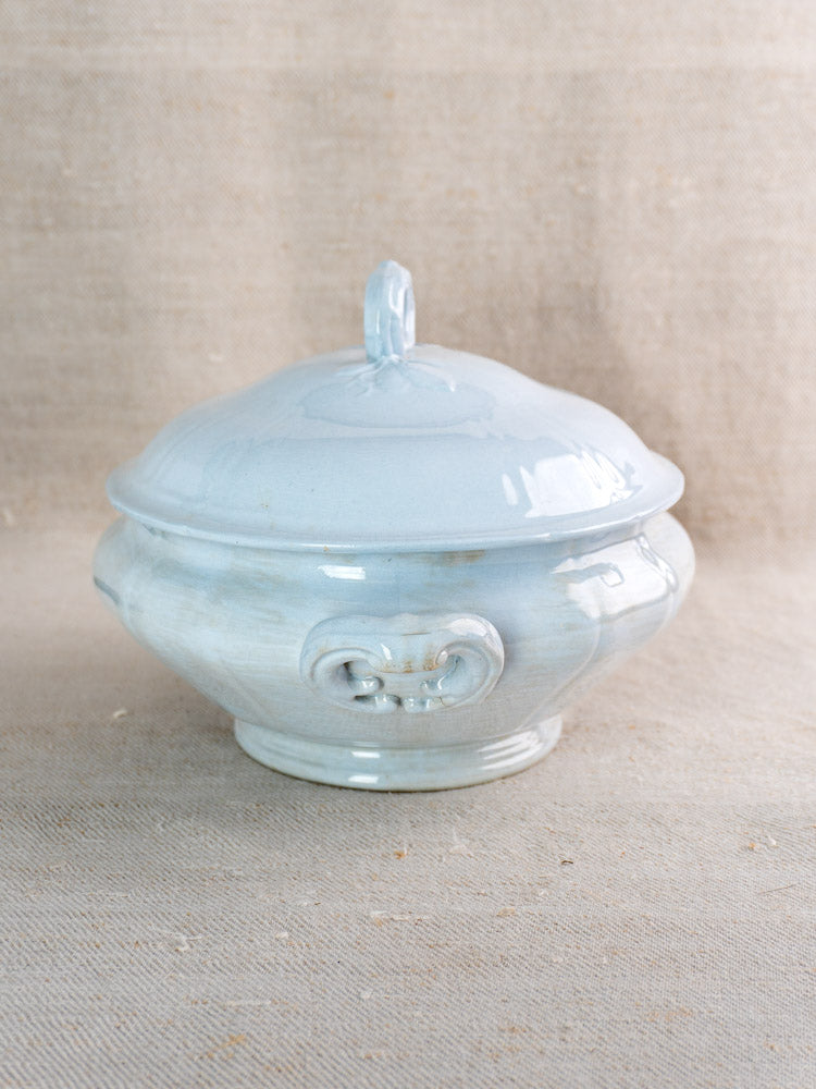 Antique Villeroy and Boch Mettlach tureen with soft blue glaze, decorative lid handle on beige fabric.