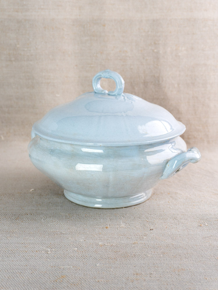 Antique Mettlach Villeroy and Boch tureen with soft blue glaze and lid on beige fabric.