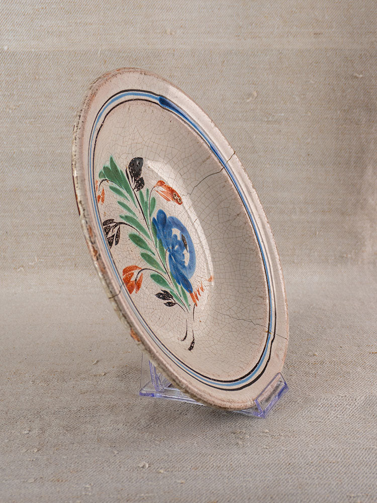 Antique French faience plate with crackled glaze, hand-painted floral motifs; shown on a clear stand, neutral backdrop.