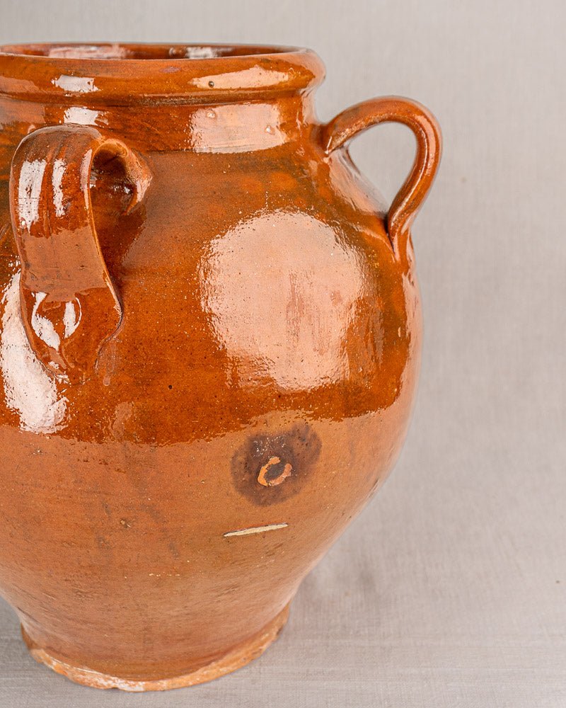 Large glossy brown 19th-century French terracotta oil jar with two rounded handles, plain gray background.